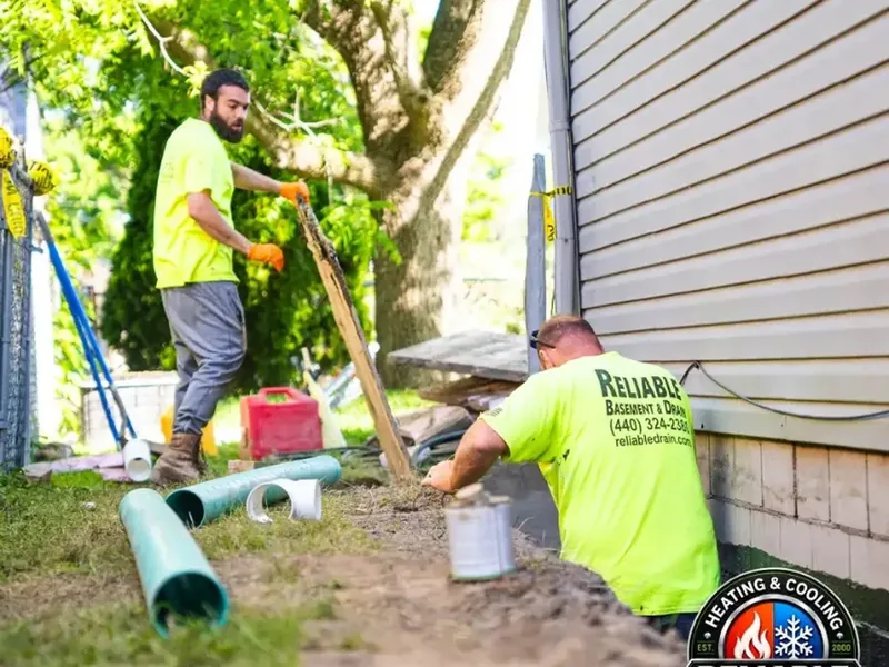Reliable crew performing exterior drainage work beside a home
